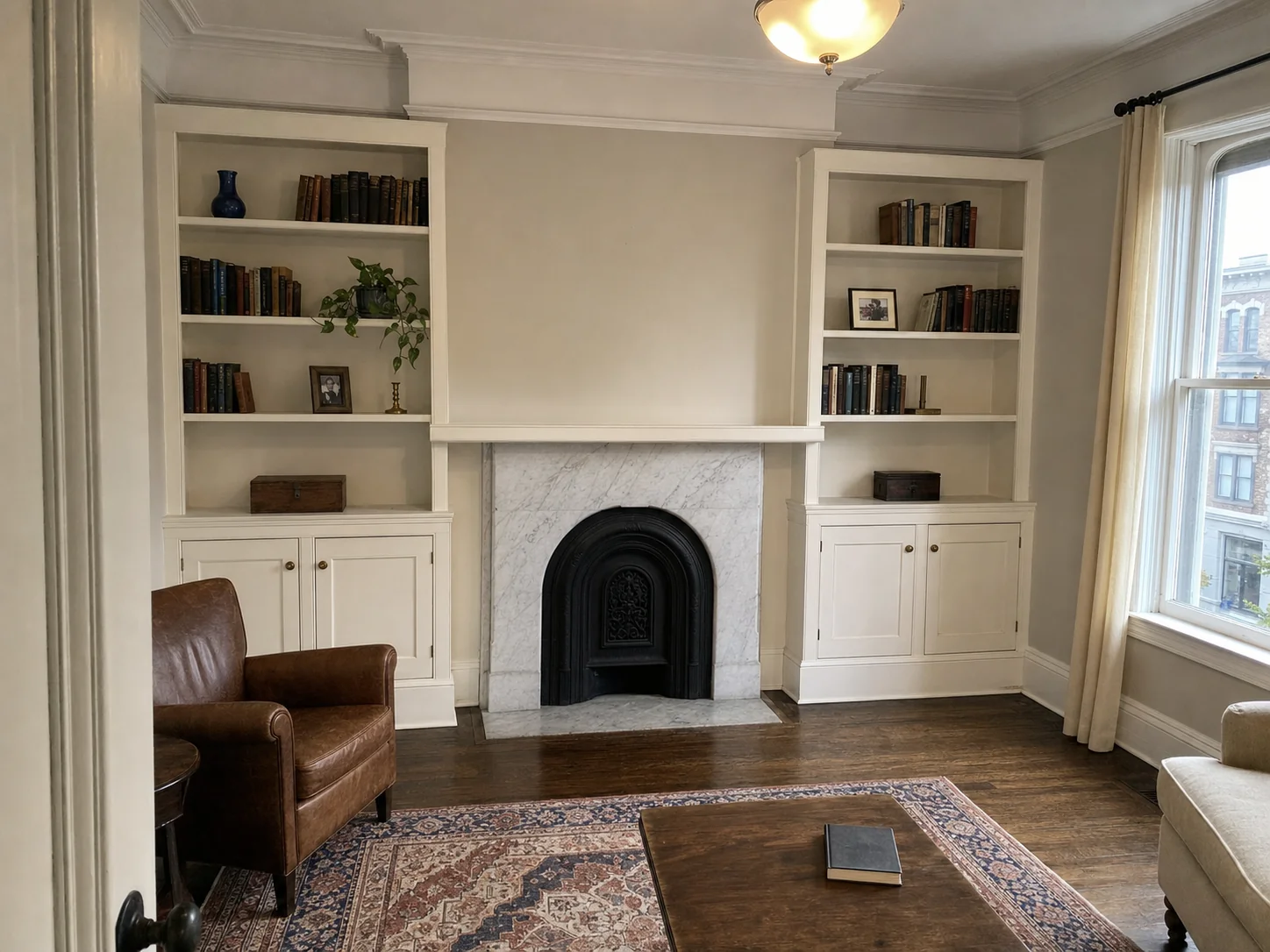 Cream built-in bookcases flanking a marble fireplace before painting in a Logan Circle, Washington DC rowhouse